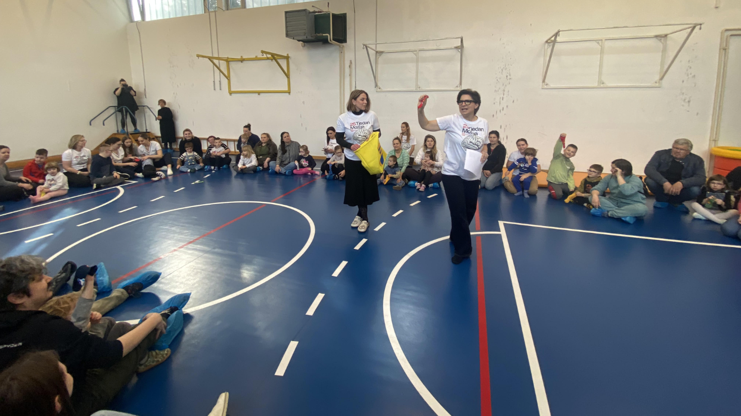 Djeca i odrasli sudjeluju u edukativnoj radionici u školskoj sportskoj dvorani.