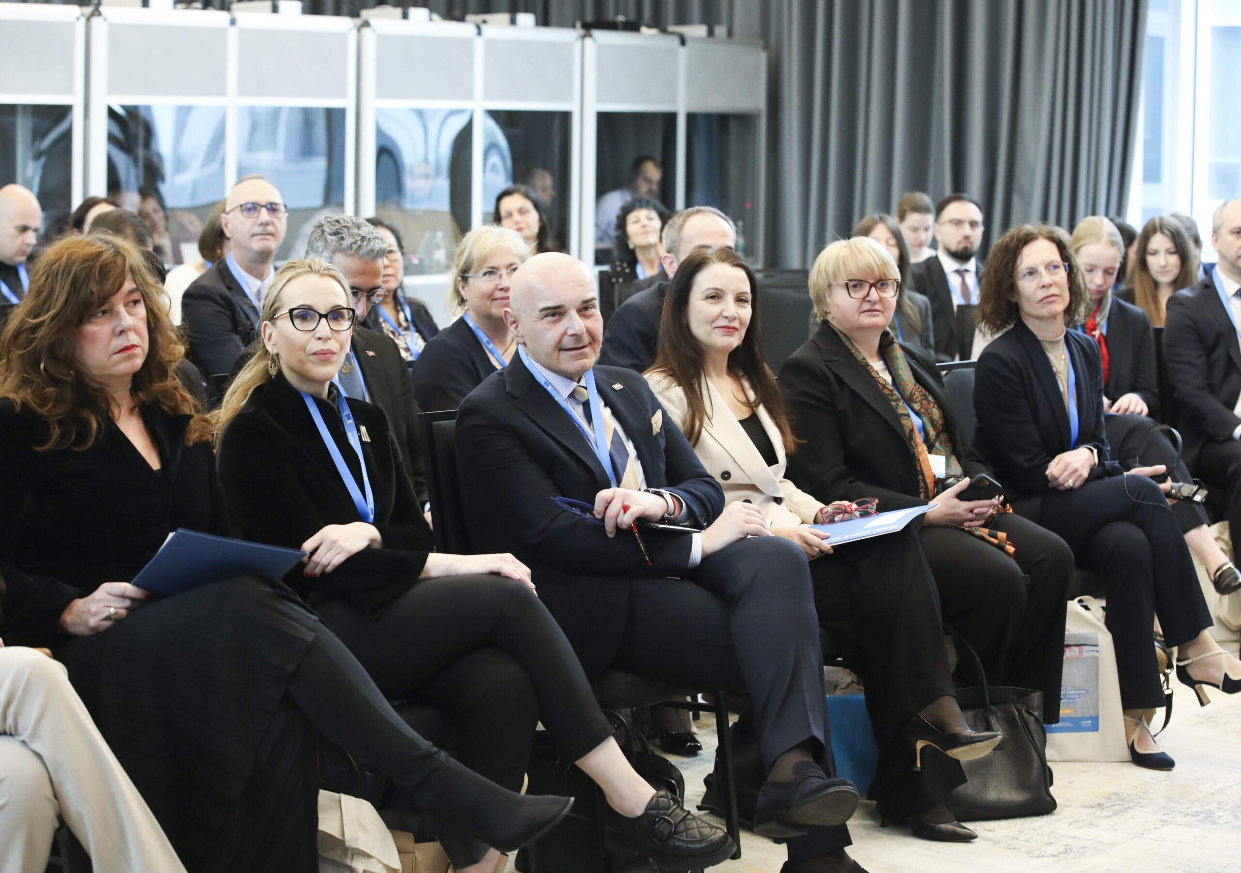 Publika na konferenciji sjedi i prati izlaganje u dvorani.