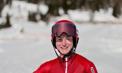 Fotografija prikazuje skijašicu s crvenom kacigom i crvenim skijaškim odjelom s kockicama.