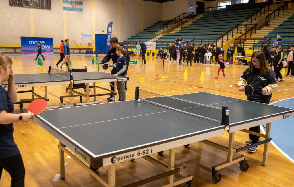 Djeca igraju stolni tenis uz vodstvo trenera u sportskoj dvorani.