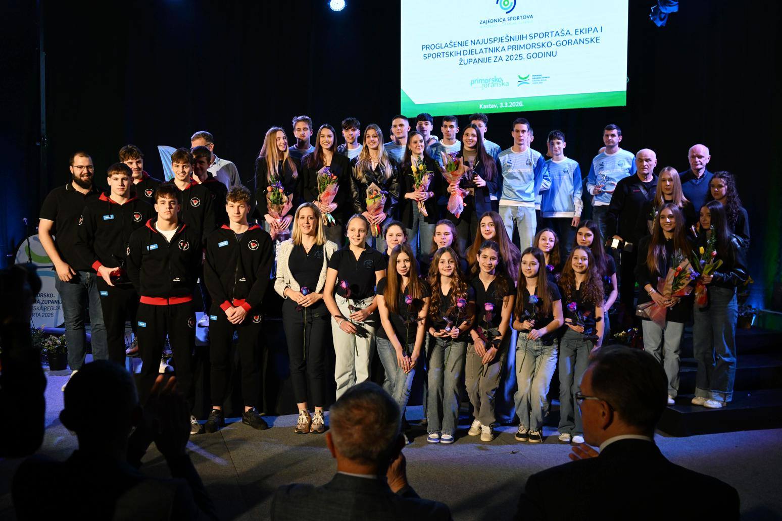 Fotografija prikazuje više osoba koje stoje na pozornici.