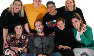 Na slici je osmero odraslih ljudi koji poziraju zajedno u opuštenoj i prijateljskoj atmosferi. Raspoređeni su u dvije razine: pet osoba stoji u stražnjem redu, dok tri osobe sjede ispred njih.