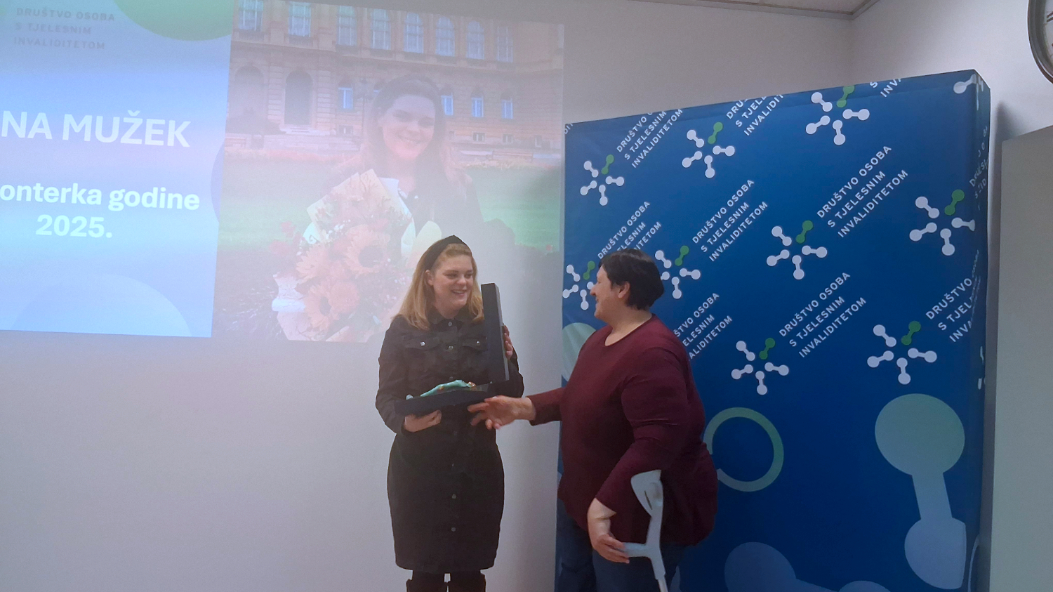 Dodjela nagrade volonterki godine uz prezentaciju u pozadini.