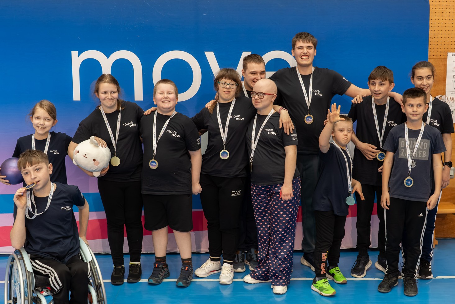 Fotografija prikazuje nekoliko djece s teškoćama u razvoju koji oko vrata imaju medalje. Jedan je dječak u kolicima, a jedna cura drži plišanu igračku.