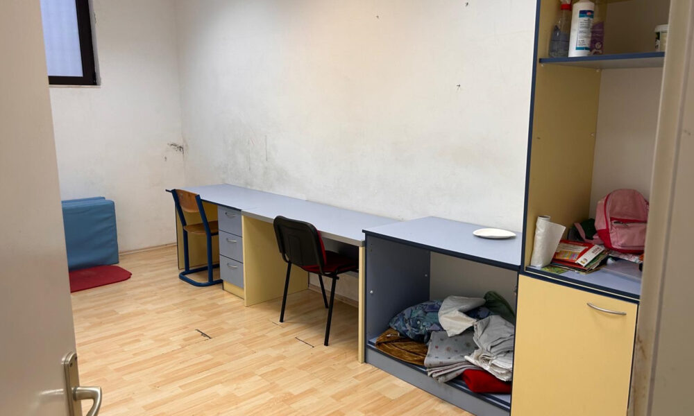 Prazna prostorija s radnim stolom, stolicama i otvorenim policama.