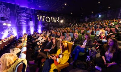 Fotografija prikazuje više ljudi u dvorani kako gleda neko događanje