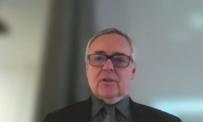 Na fotografiji se nalazi stariji muškarac koji gleda izravno u kameru. Ima kratku sijedu kosu i nosi naočale. Odjeven je formalno – u tamno odijelo, košulju i kravatu. Izraz lica mu je neutralan, a pozadina je jednostavna i svijetla, bez puno detalja, što sugerira da se radi o snimci u zatvorenom prostoru, vjerojatno tijekom online sastanka ili predavanja.