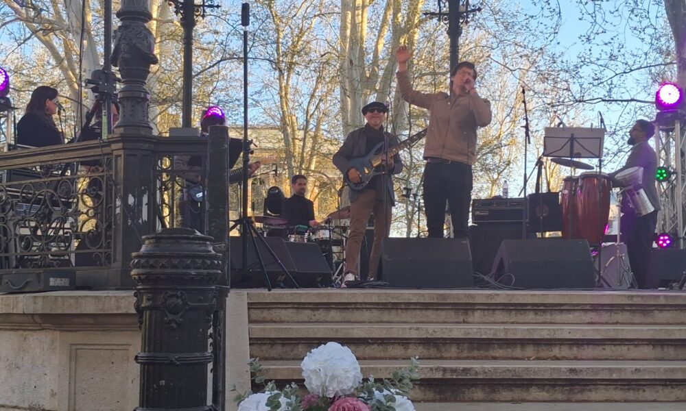 Fotografija prikazuje tamnopute pjevače kako nastupaju na otvorenom.