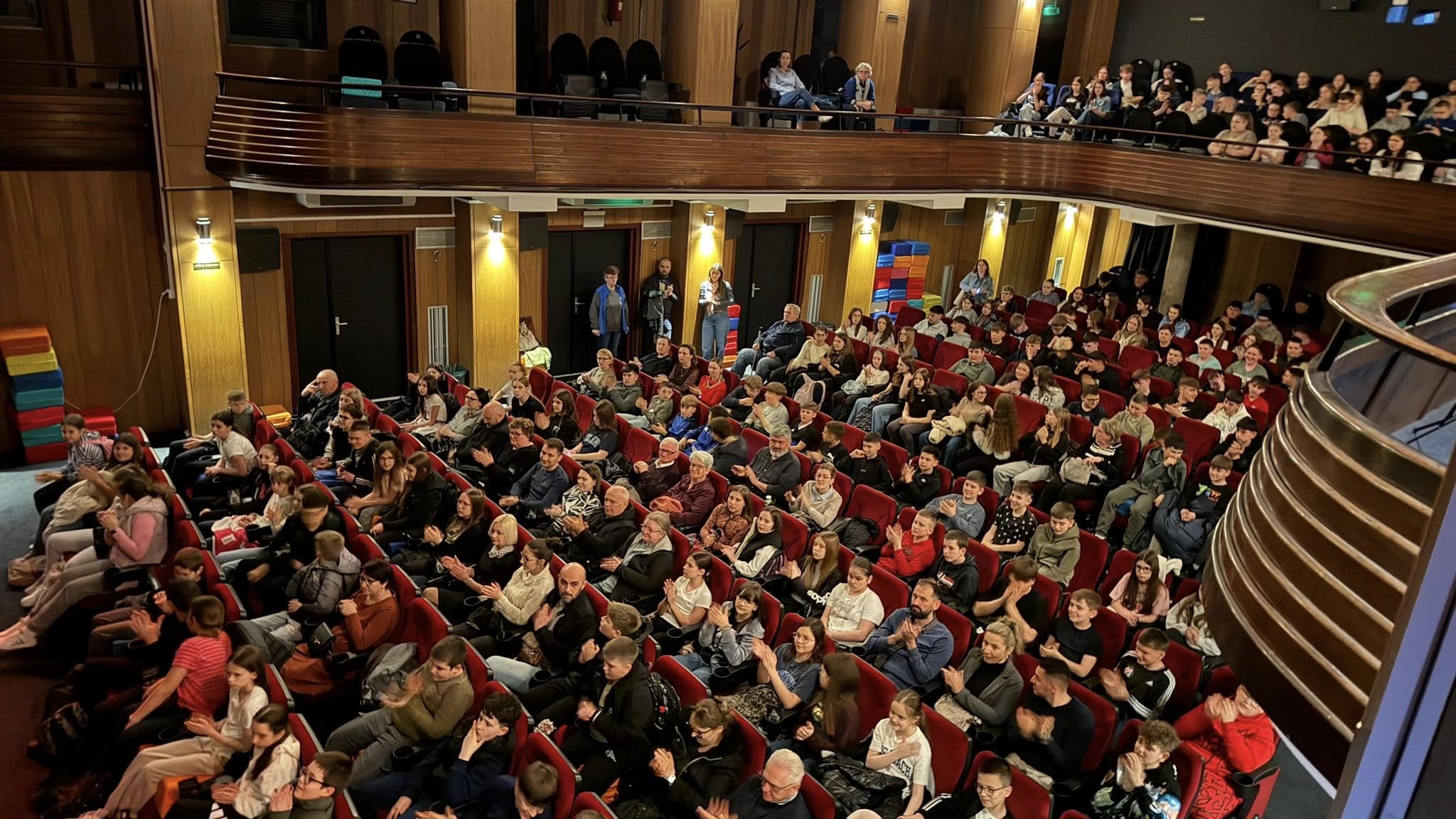Fotografija prikazuje ljude kako sjede u kazalištu.