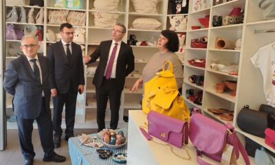 Fotografija prikazuje nekoliko ljudi u dućanu s raznim stvarima, a u prvom planu su torbe.