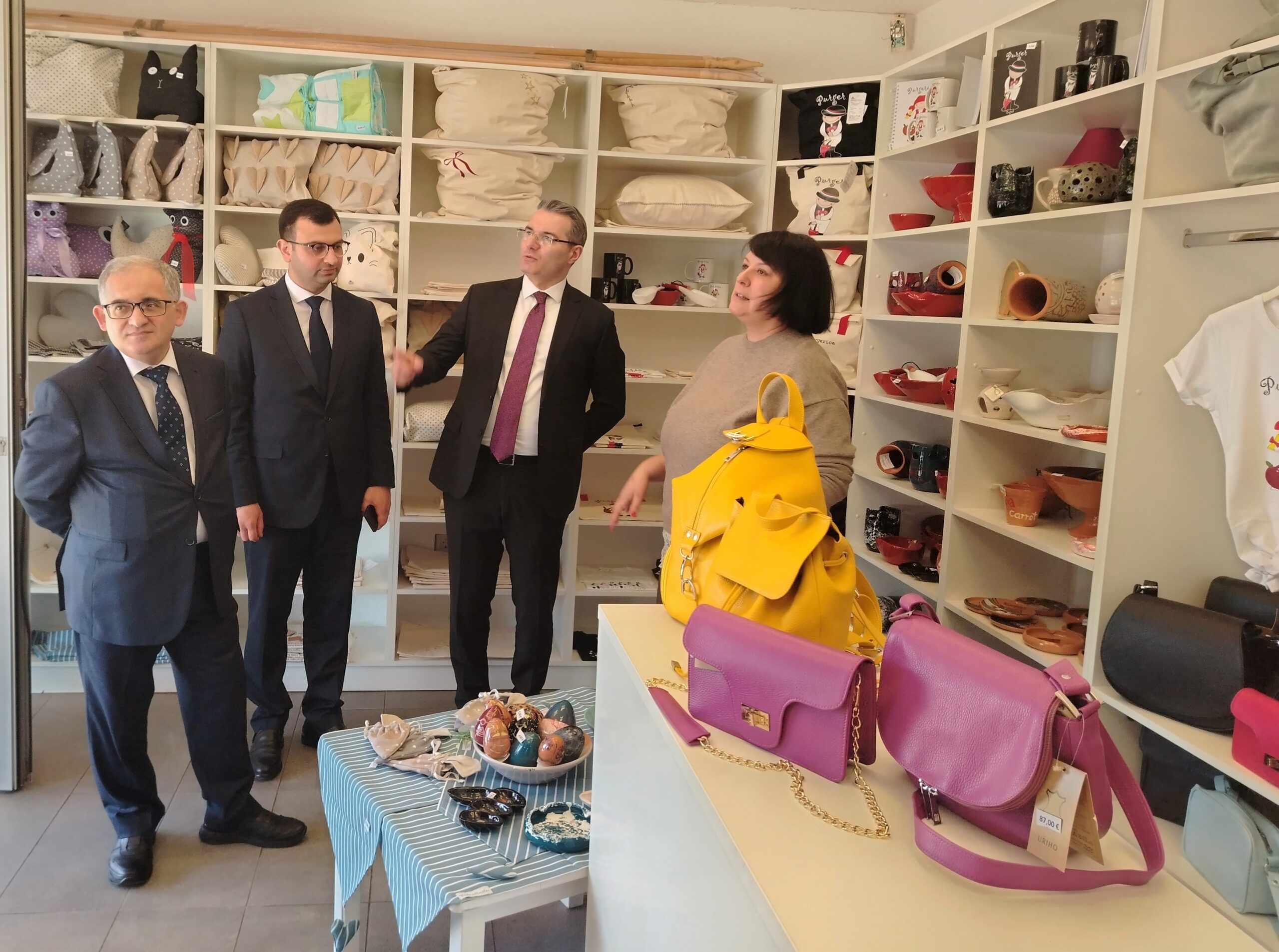 Fotografija prikazuje nekoliko ljudi u dućanu s raznim stvarima, a u prvom planu su torbe.