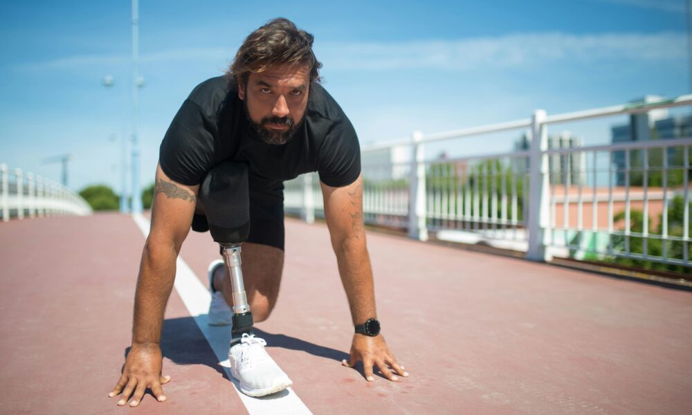 Fotografija prikazuje čovjeka koji je u niskom startu za početak trčanja. On umjesto desne potkoljenice ima protezu.