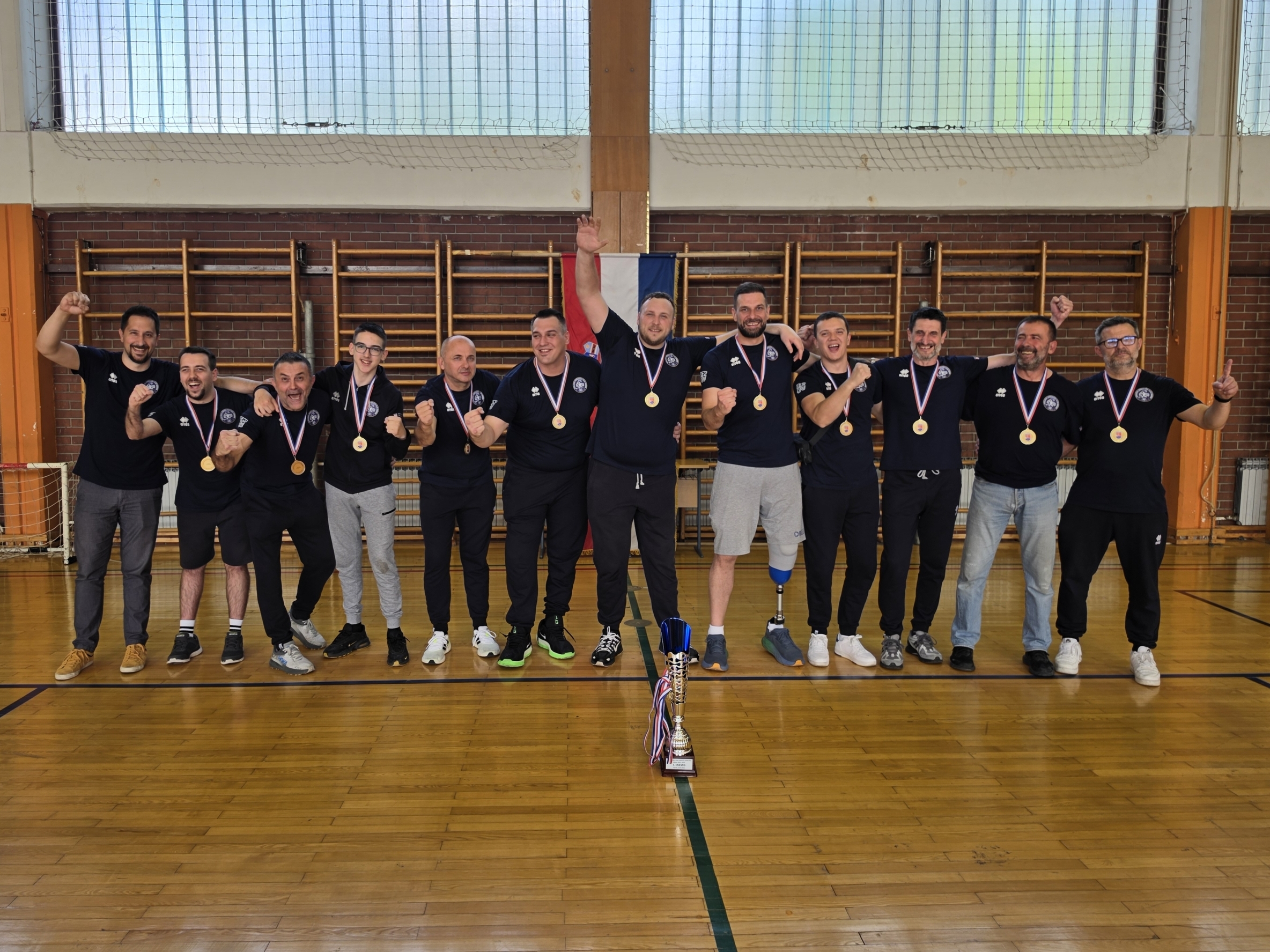 Fotografija prikazuje više ljudi, a ispred njih pehar.