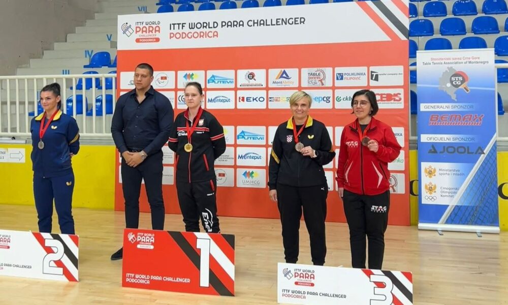 Fotografijha prikazuje nekoliko ljudi u paru po dvoje kako stoje na postolju s medaljamaoko vrata.