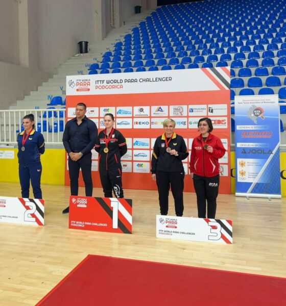 Fotografijha prikazuje nekoliko ljudi u paru po dvoje kako stoje na postolju s medaljamaoko vrata.