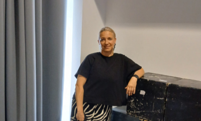 Žena stoji uz kutije u unutarnjem prostoru i gleda prema kameri.
