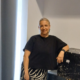 Žena stoji uz kutije u unutarnjem prostoru i gleda prema kameri.