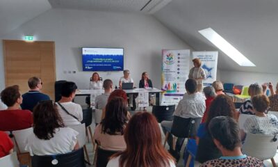 Na fotografiji je prikazan trenutak s početne konferencije projekta „Snaga različitosti“, održane u Multimedijskoj dvorani Kina Edison u Karlovcu. U prvom planu vidi se publika okupljena u dvorani, dok se u pozadini nalaze sudionice panela koje predstavljaju projekt i njegove aktivnosti. Jedna od govornica obraća se prisutnima, a iza nje su postavljeni promotivni roll-up plakati i ekran s nazivom projekta. Atmosfera djeluje radno i svečano, uz velik interes sudionika za teme socijalne uključenosti, podrške osobama s invaliditetom i razvoja socijalnih usluga u zajednici.