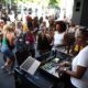 DJ-ica pušta glazbu na otvorenom dok okupljeni plešu i druže se.