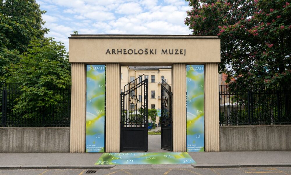 Ulaz u Arheološki muzej u Zagrebu s otvorenim vratima i vizualima izložbe u Lapidariju.
