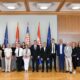 Na fotografiji je snimljena skupina ljudi tijekom službenog susreta u reprezentativnoj dvorani s drvenim zidnim oblogama. U sredini stoji predsjednik Republike, okružen predstavnicima Hrvatskog saveza gluhoslijepih osoba Dodir i drugim sudionicima sastanka. Iza okupljenih nalaze se zastave Republike Hrvatske i Europske unije, što naglašava službeni karakter događaja. Sudionici su poredani u jednom redu i poziraju za zajedničku fotografiju. Većina je odjevena u poslovnu ili svečanu odjeću, a svi gledaju prema kameri s ozbiljnim ili blagim osmijehom. Fotografija prikazuje završetak ili dio protokolarnog susreta održanog povodom obilježavanja Međunarodnog dana gluhosljepoće.