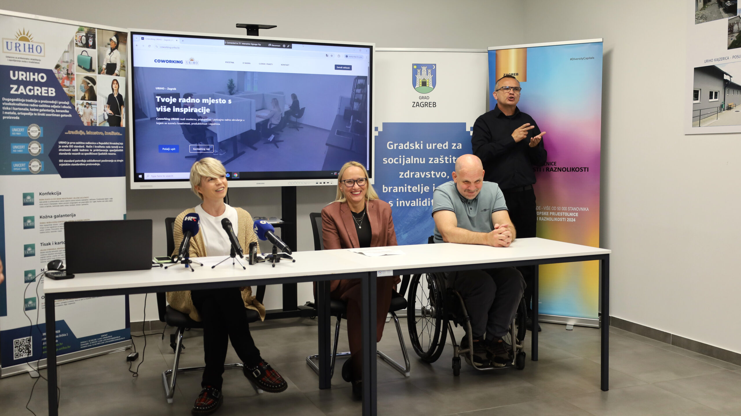 Predstavnici URIHO-a, Grada Zagreba i partnera sudjeluju na predstavljanju novog coworking prostora namijenjenog profesionalnom razvoju i zapošljavanju osoba s invaliditetom, dok prevoditelj znakovnog jezika osigurava pristupačnost događaja.