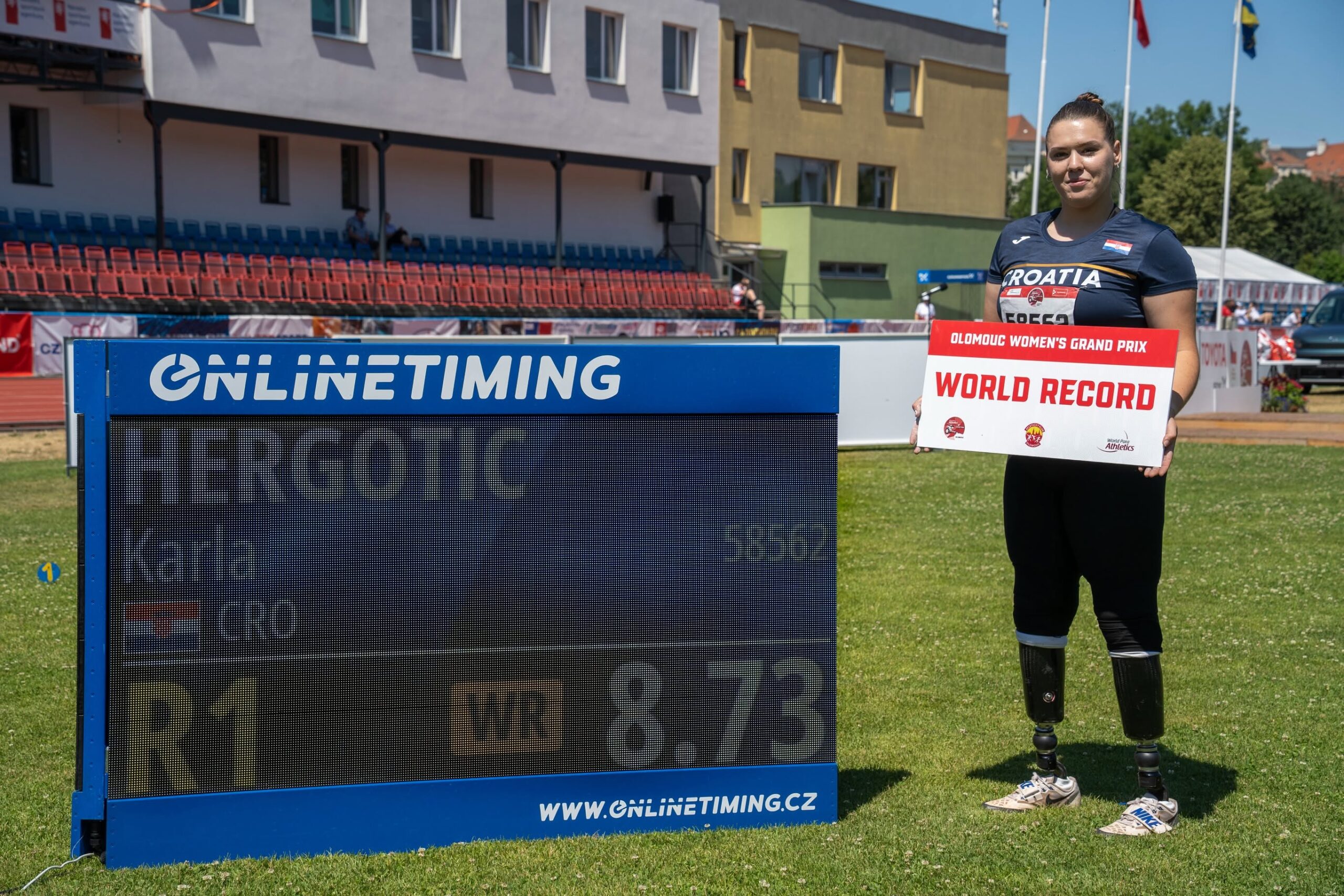 Hrvatska paraatletičarka drži ploču s natpisom "World Record" na atletskom stadionu.