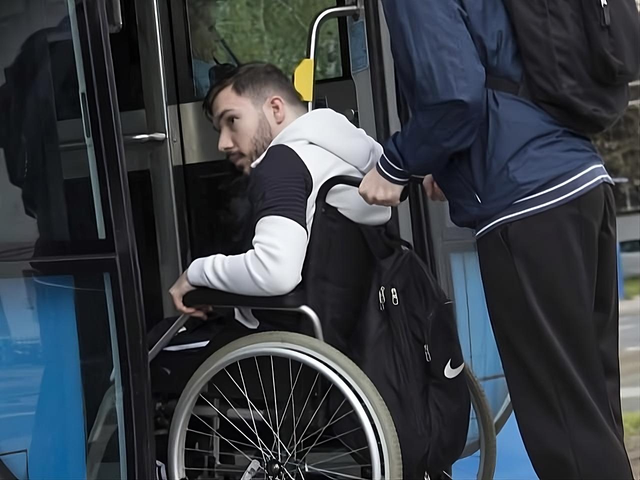 Na fotografiji se vidi osoba u invalidskim kolicima kojoj druga osoba pomaže pri ulasku u niskopodni autobus. Osoba u kolicima nalazi se na ulazu u vozilo i jednom rukom pridržava okvir vrata, dok je iza nje osoba koja gura kolica i pomaže pri ukrcaju. Fotografija naglašava važnost pristupačnog javnog prijevoza i uloge osobne asistencije u omogućavanju samostalnijeg kretanja osoba s invaliditetom. Prikazuje svakodnevnu situaciju u kojoj prilagođena vozila i podrška druge osobe omogućuju lakše korištenje javnog prijevoza.