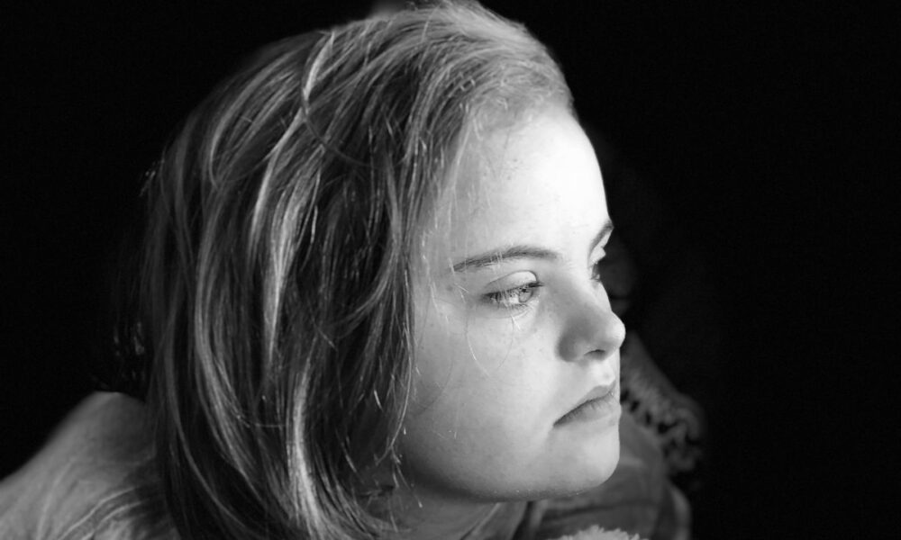 Crno-bijeli portret mlade djevojke koja gleda udesno, dok joj bočno svjetlo obasjava lice. Izraz lica djeluje zamišljeno, a pozadina je tamna, čime je naglasak stavljen na njezin profil.