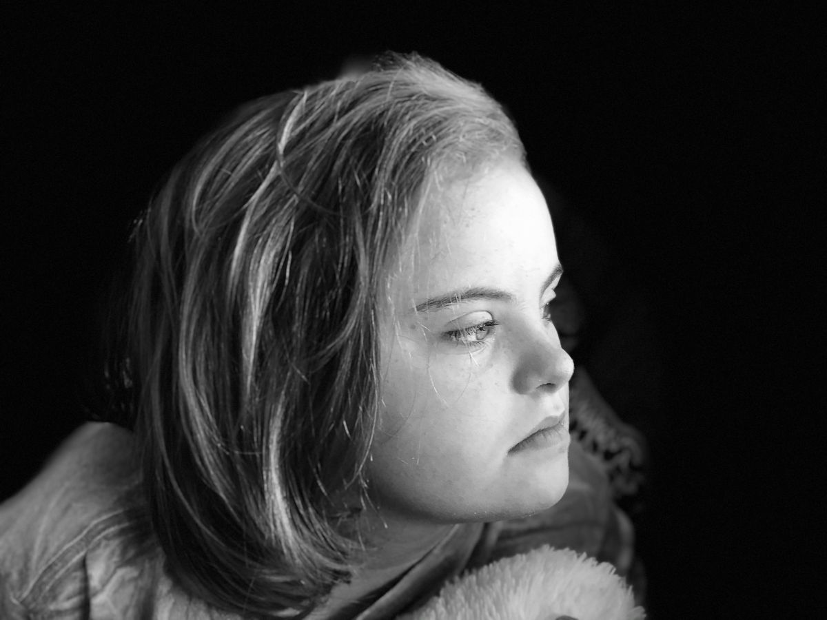 Crno-bijeli portret mlade djevojke koja gleda udesno, dok joj bočno svjetlo obasjava lice. Izraz lica djeluje zamišljeno, a pozadina je tamna, čime je naglasak stavljen na njezin profil.