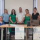 Na fotografiji je zabilježeno predstavljanje projekta „Moja mreža podrške“ u prostorijama Društva distrofičara Istre. Za stolom i ispred promotivnog panoa pozira sedam članova projektnog tima i suradnika, dok je jedna sudionica u prvom planu u invalidskim kolicima. Na stolu se nalaze prijenosno računalo, zvučnik i promotivni materijali projekta, a na prednjoj strani stola istaknuti su plakati s nazivom projekta. U pozadini se vidi projekcijsko platno te zid ukrašen dječjim likovnim radovima, što prostoru daje ugodnu i zajedničku atmosferu. Fotografija simbolizira početak provedbe projekta usmjerenog na pružanje podrške osobama s invaliditetom i njihovim obiteljima.