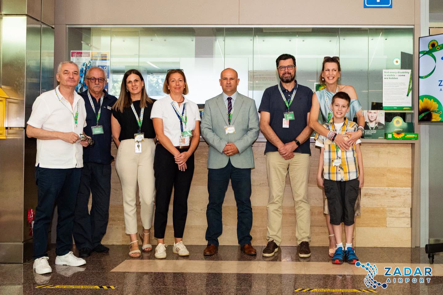 Na fotografiji se nalazi osam osoba koje poziraju u prostoru Zračne luke Zadar, ispred staklenog zida i informacijskog pulta. Skupinu čine zaposlenici zračne luke, predstavnici uključeni u projekt te žena s dječakom, koji stoje na desnoj strani fotografije. Većina prisutnih nosi akreditacije oko vrata, što upućuje na službeni događaj ili predstavljanje nove inicijative. U pozadini su vidljivi promotivni plakati programa Hidden Disabilities Sunflower sa simbolom suncokreta, uključujući poruku na engleskom jeziku: "Not every disability is visible – some are hidden" ("Nije svaki invaliditet vidljiv – neki su nevidljivi"). Na desnoj strani nalazi se i zaslon s logotipom Zračne luke Zadar i motivom suncokreta. Svi sudionici gledaju prema kameri i nasmiješeni su, ostavljajući dojam svečanog obilježavanja pristupanja Zračne luke Zadar programu Hidden Disabilities Sunflower. U donjem desnom kutu fotografije nalazi se logotip Zadar Airporta.