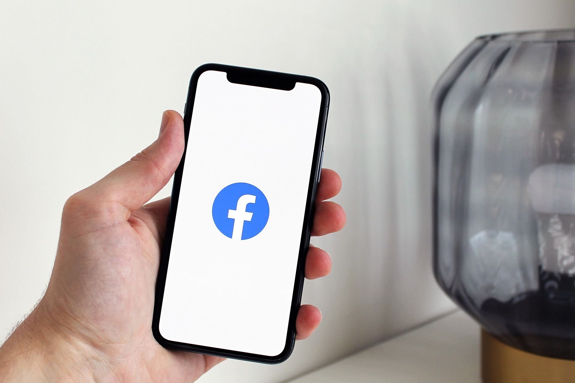 Ruka drži pametni telefon na čijem je zaslonu prikazan logotip Facebooka.