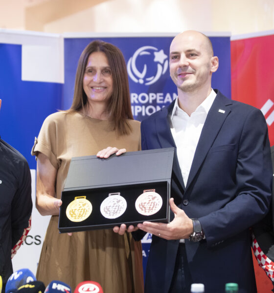 Četvero ljudi pozira na konferenciji za medije držeći kutiju sa zlatnom, srebrnom i brončanom medaljom.