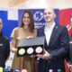 Četvero ljudi pozira na konferenciji za medije držeći kutiju sa zlatnom, srebrnom i brončanom medaljom.