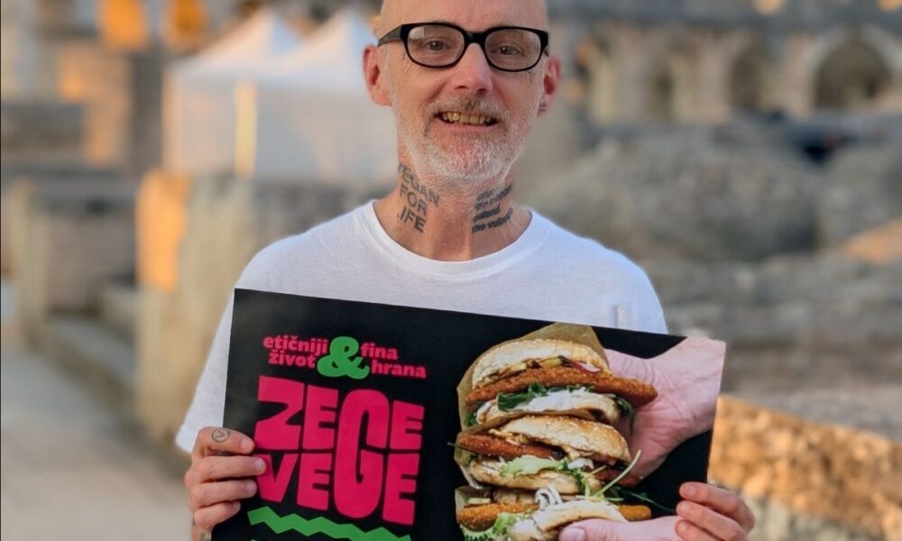 Muškarac drži plakat festivala ZeGeVege, a u pozadini se vidi pulska Arena.