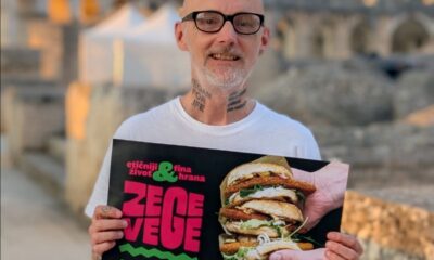 Muškarac drži plakat festivala ZeGeVege, a u pozadini se vidi pulska Arena.
