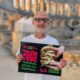 Muškarac drži plakat festivala ZeGeVege, a u pozadini se vidi pulska Arena.