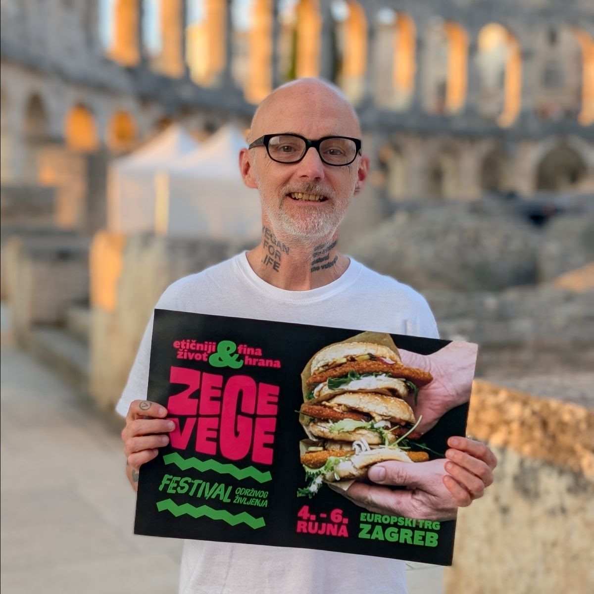 Muškarac drži plakat festivala ZeGeVege, a u pozadini se vidi pulska Arena.