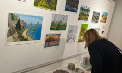 Posjetiteljica razgledava izložene likovne radove i predmete u galerijskom prostoru.