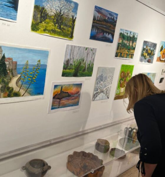 Posjetiteljica razgledava izložene likovne radove i predmete u galerijskom prostoru.