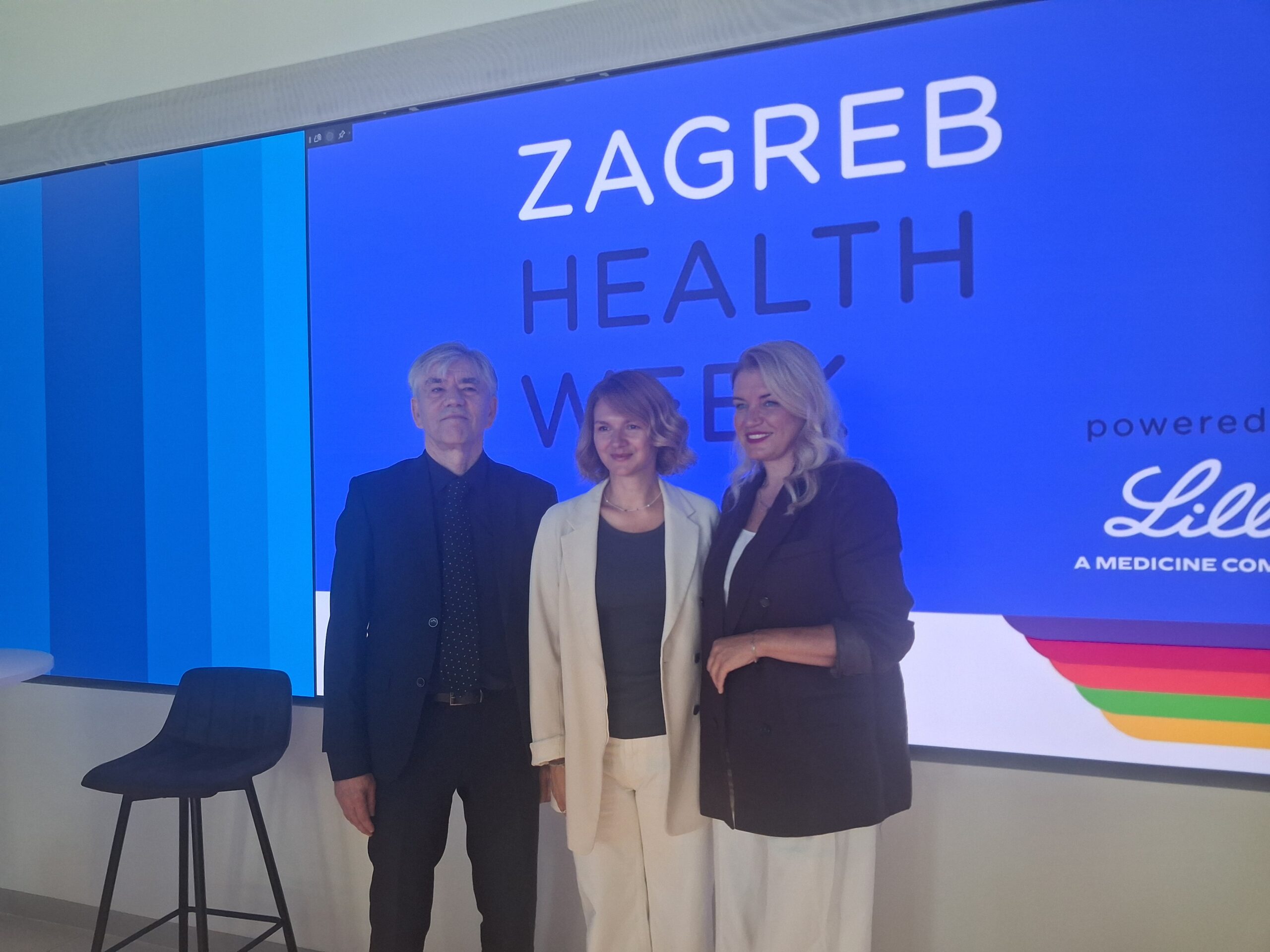 Troje sudionika pozira ispred zaslona s natpisom ‘Zagreb Health Week’.