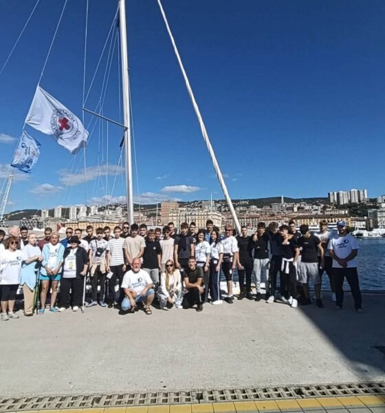 Na fotografiji je velika skupina sudionika projekta „Jedra duha“ okupljena na riječkoj rivi, ispred jedrilice. U prvom planu stoje i sjede sudionici različitih generacija, a među njima su i mladi sudionici te članovi organizacijskog i partnerskog tima. U pozadini se vidi riječki zaljev s gradskom obalom i prepoznatljivom panoramom Rijeke. Na jedrilici se vijore zastave Hrvatskog Crvenog križa i projekta, dok vedro nebo i sunčano vrijeme stvaraju vedru atmosferu. Fotografija dobro prikazuje zajedništvo, inkluziju i druženje sudionika projekta „Jedra duha“, kao i povezanost projekta s morem i jedrenjem.