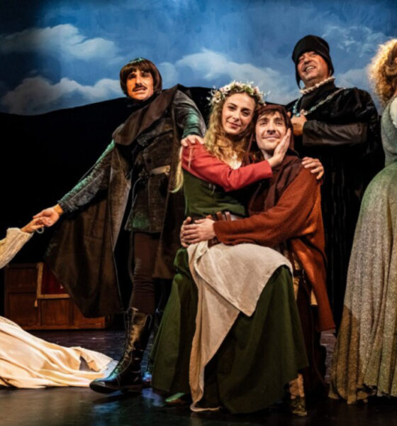 Glumci u povijesnim kostimima izvode scenu kazališne predstave na pozornici.