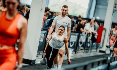 Sportašica s girjom u ruci tijekom natjecanja, uz trenera koji stoji iza nje.