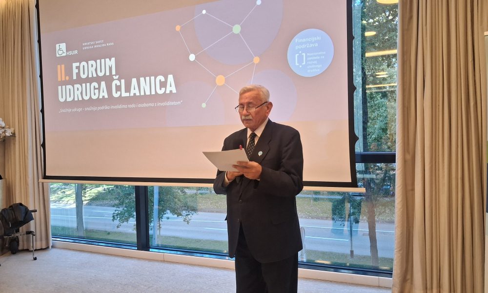 Muškarac u odijelu čita govor na II. forumu udruga članica Hrvatskog saveza udruga invalida rada.