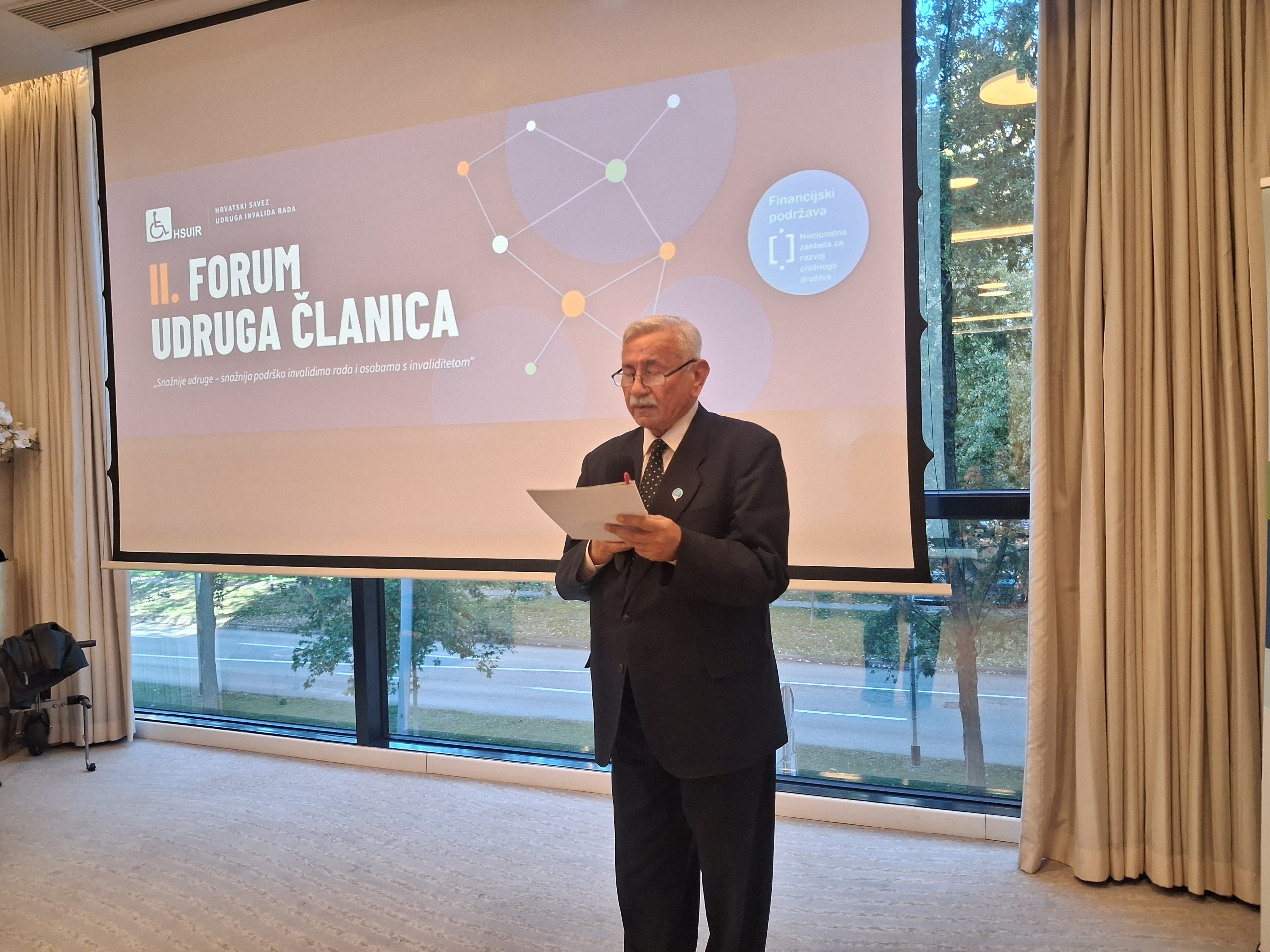 Muškarac u odijelu čita govor na II. forumu udruga članica Hrvatskog saveza udruga invalida rada.