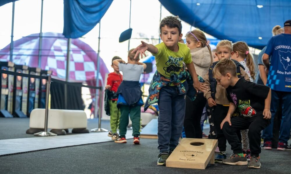Fotografija prikazuje dječaka kako baca vrećicu i nastoji nešto pogoditi. Pokraj njega je više djece.