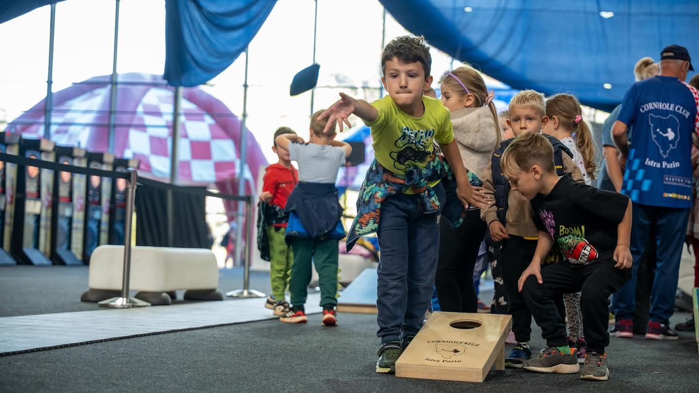 Fotografija prikazuje dječaka kako baca vrećicu i nastoji nešto pogoditi. Pokraj njega je više djece.