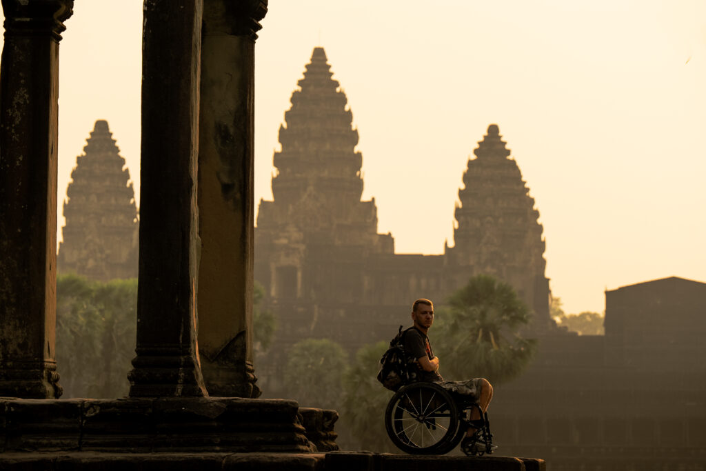 Muškarac u invalidskim kolicima pozira ispred hrama Angkor Wat u Kambodži.